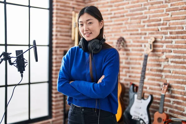 Chinese woman artist smiling confident standing with arms crossed gesture at music studio