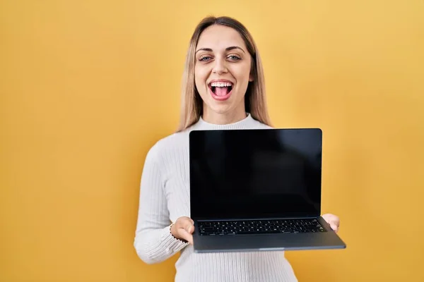 stock image Young blonde woman holding laptop smiling and laughing hard out loud because funny crazy joke. 