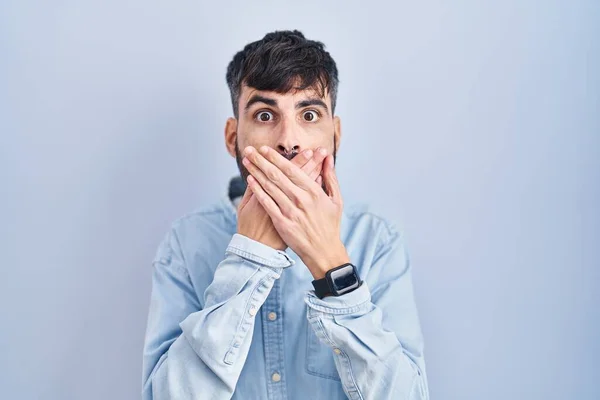 Young Hispanic Man Beard Standing Blue Background Shocked Covering Mouth — Foto Stock