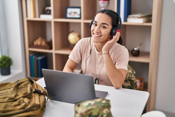 若いですヒスパニック系女性軍隊兵士使用ノートパソコンとヘッドフォンで自宅 — ストック写真