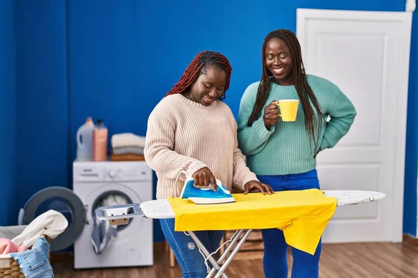 African American Women Ironing Clothes Drinking Coffee Laundry Room — Stock Photo, Image