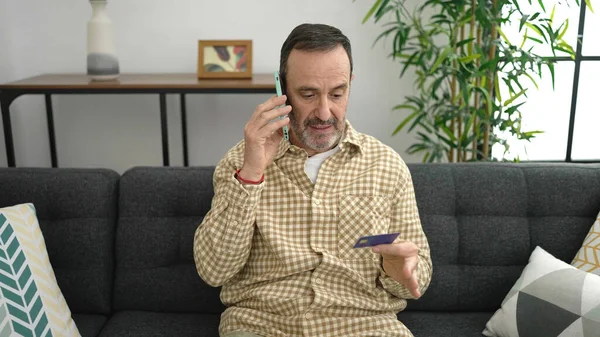 Muž Středního Věku Mluví Smartphone Držící Kreditní Kartu Doma — Stock fotografie