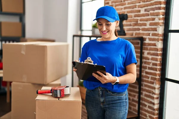 Middle age woman moving worker writing on checklist at new home