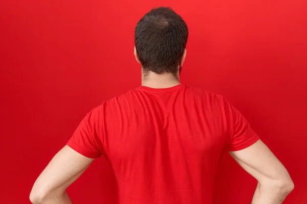 Junger Hispanischer Mann Lässigem Rotem Shirt Steht Rückwärts Und Blickt — Stockfoto