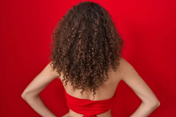 Hispanic Woman Curly Hair Standing Red Background Standing Backwards Looking — Stok fotoğraf