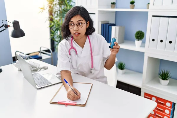 Young Latin Woman Wearing Doctor Uniform Holding Inhaler Writing Clipboard — Stock Photo, Image