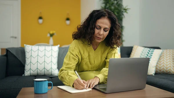 Middle Age Hispanic Woman Using Laptop Writing Notebook Home — ストック写真