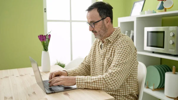 中年男を使用してノートパソコンを使用してテーブルの上に家に座って — ストック写真