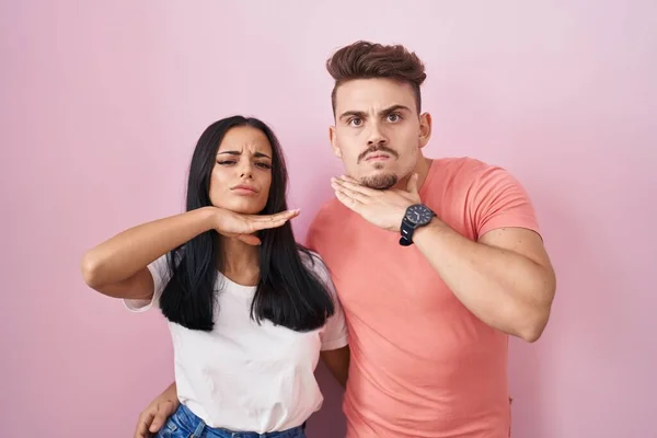 Young Hispanic Couple Standing Pink Background Cutting Throat Hand Knife — Fotografia de Stock