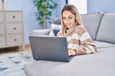 Young woman using laptop sitting on floor at home