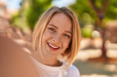 Young blonde woman smiling confident make selfie by camera at street