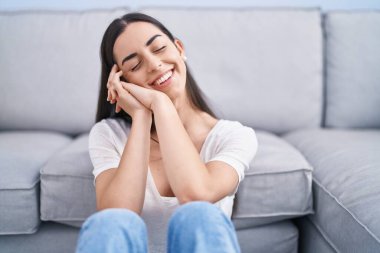 Genç İspanyol kadın evde oturmuş kendinden emin gülümsüyor.