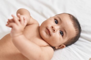Adorable hispanic baby lying on bed at bedroom