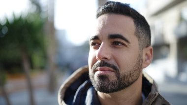 Latin kökenli genç adam ciddi bir ifadeyle sokağa bakıyor.