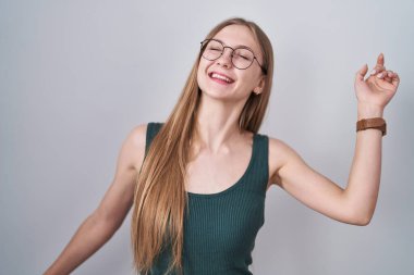 Young caucasian woman standing over white background dancing happy and cheerful, smiling moving casual and confident listening to music 