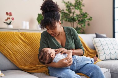 Mother and son hugging each other sitting on sofa at home