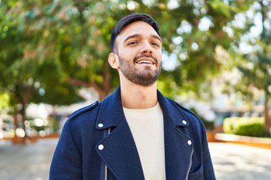 Parkta kendinden emin gülümseyen İspanyol genç adam.