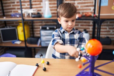 Adorable hispanic boy astronomer student make planetary work at laboratory classroom