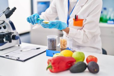 Genç ve güzel İspanyol bilim kadını laboratuardaki elma parçasına sıvı döküyor.