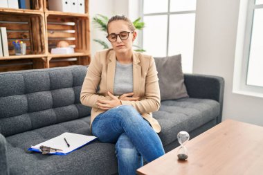Muayenehanede çalışan genç bir kadın midesi üzerinde çalışıyor çünkü hazımsızlık, acı verici bir hastalık ve kendini iyi hissetmiyor. Ağrı kavramı. 