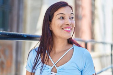 Young beautiful hispanic woman smiling confident looking to the side at street
