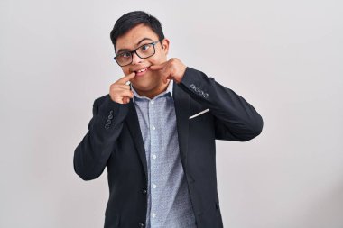 Down sendromlu genç İspanyol adam iş stili giyiniyor neşeli gülüyor ve parmaklarıyla ve ağzıyla işaret ediyor. diş sağlığı kavramı. 