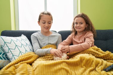 Two kids eating popcorn watching movie at home