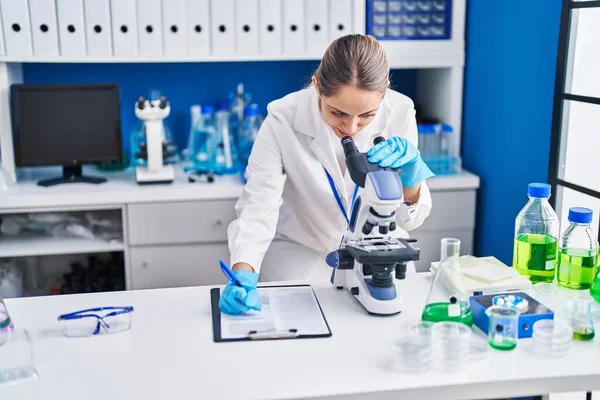 Ung Kvinnlig Forskare Med Hjälp Mikroskop Skriva Rapport Laboratorium — Stockfoto