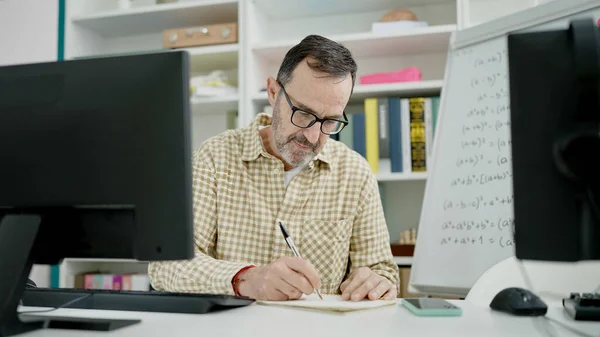 教室でノートに書くコンピュータを使用している中年の男性教師 — ストック写真