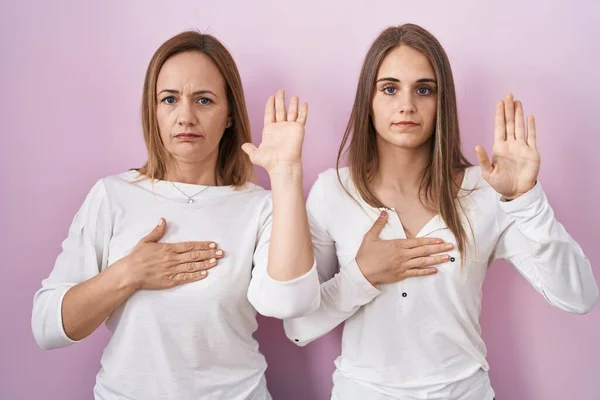 Middle Age Mother Young Daughter Standing Pink Background Swearing Hand — Stock Photo, Image
