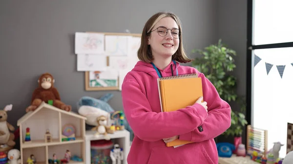 Young Blonde Woman Preschool Teacher Smiling Confident Holding Books Kindergarten — Stockfoto