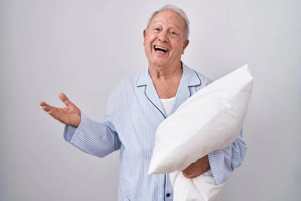 Senior Man Grey Hair Wearing Pijama Hugging Pillow Pointing Aside — Zdjęcie stockowe