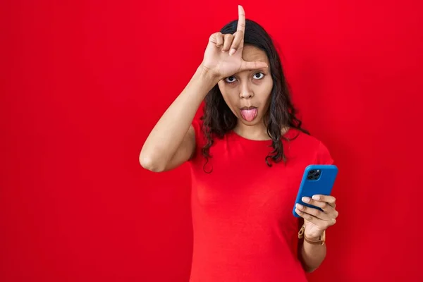 Young Brazilian Woman Using Smartphone Red Background Making Fun People — Stockfoto