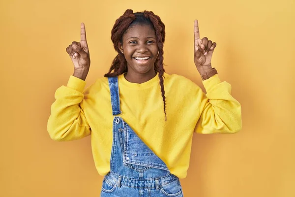 Африканська Жінка Стояла Над Жовтим Фоном Посміхаючись Вражена Здивована Вказуючи — стокове фото
