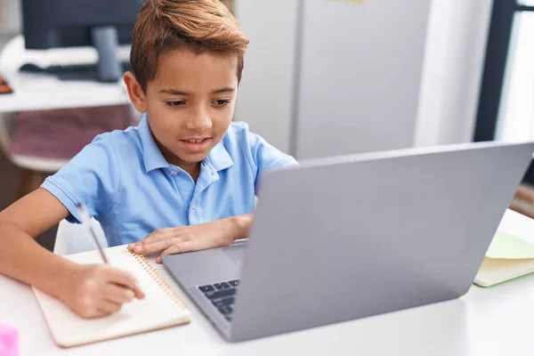 在课堂上用电脑在笔记本上写字的惊慌失措的男孩是可敬的 — 图库照片
