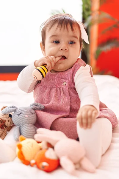 愛らしいHispanic赤ん坊Bitting Maraca座っています上のベッドルームで — ストック写真