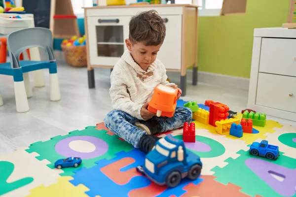 愛らしいヒスパニック幼児遊びとともに車おもちゃ座っています床に幼稚園 — ストック写真