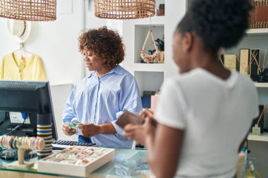 African american women shop assistant and customer speaking at clothing store