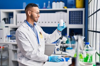 African american man scientist smiling confident weighing pills at laboratory