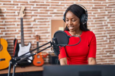 Genç Afrikalı Amerikalı kadın müzisyen müzik stüdyosunda piyano çalıyor.