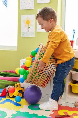 Sevimli beyaz çocuk anaokulunda toplarla oynarken gülümsüyor.