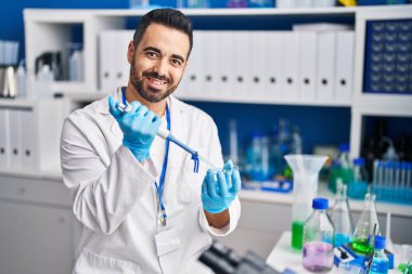 Genç İspanyol bilim adamı laboratuarda çalışırken gülümsüyor.