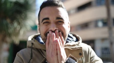 Young hispanic man standing with surprise expression at street