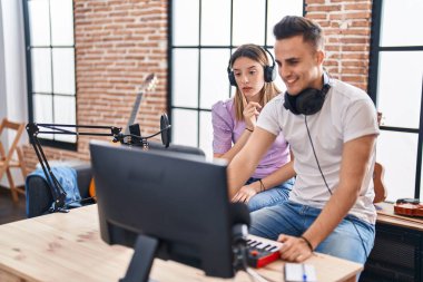 Erkek ve kadın müzisyenler müzik stüdyosunda beste yapıyorlar.