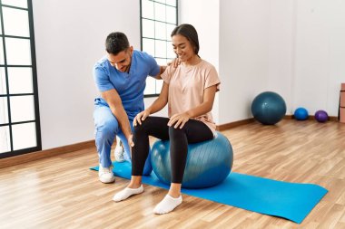 Latin erkek ve kadın fizyoterapist üniforması giyiyorlar rehabilitasyon merkezinde sağlıklı top kullanıyorlar.