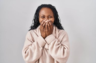 African woman standing over white background laughing and embarrassed giggle covering mouth with hands, gossip and scandal concept 
