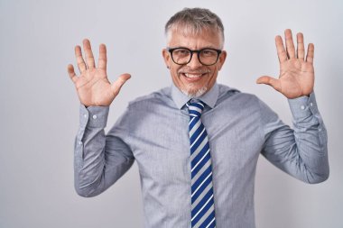 Hispanic business man with grey hair wearing glasses showing and pointing up with fingers number ten while smiling confident and happy. 