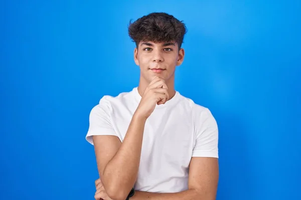 Hispanic Teenager Standing Blue Background Hand Chin Thinking Question Pensive — Foto de Stock