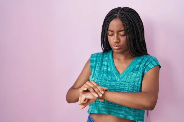 Молодий Афроамериканський Американець Косами Стоять Над Рожевим Тлом Перевіряє Час — стокове фото