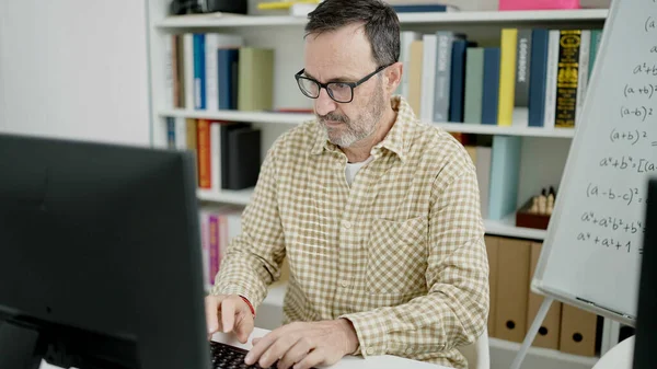教室で働いているコンピュータを使っている中年の男性教師 — ストック写真